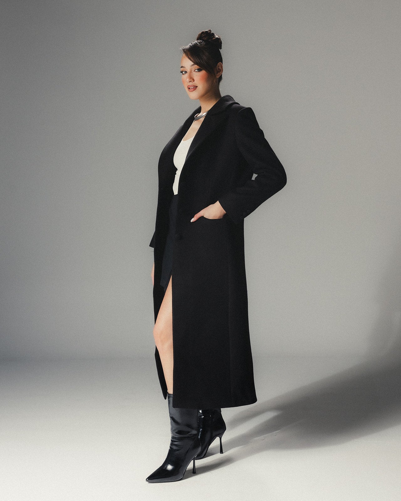 Side view of MYSHA Obsidian black premier wool coat with plush detachable fur collar on a high-fashion model.