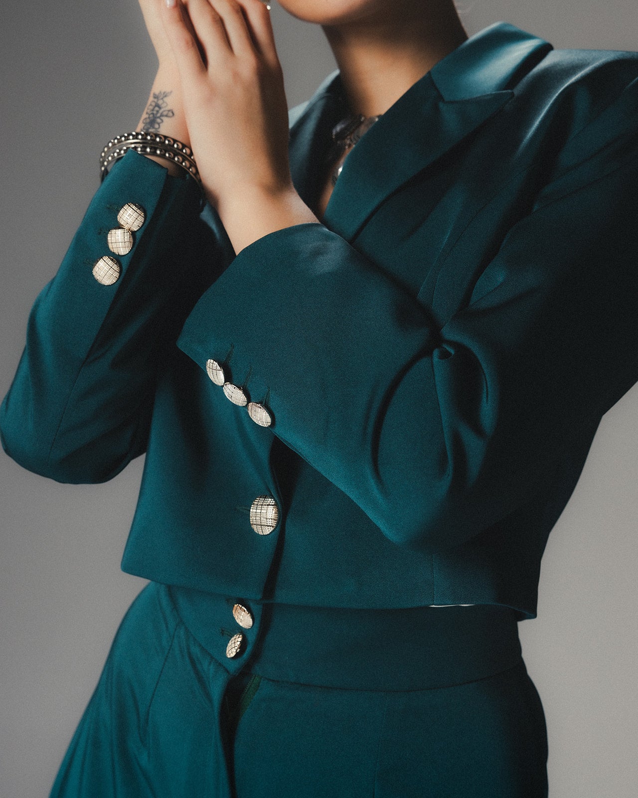 Front view of MYSHA Emerald green cropped blazer in luminous satin crepe featuring sharp lapels and silver-toned statement buttons.