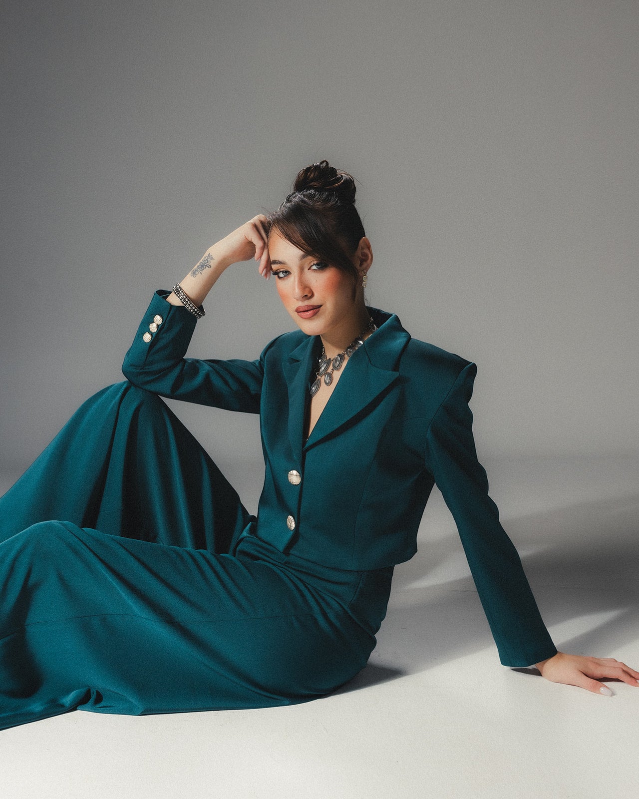 Front view of MYSHA Emerald green cropped blazer in luminous satin crepe featuring sharp lapels and silver-toned statement buttons.