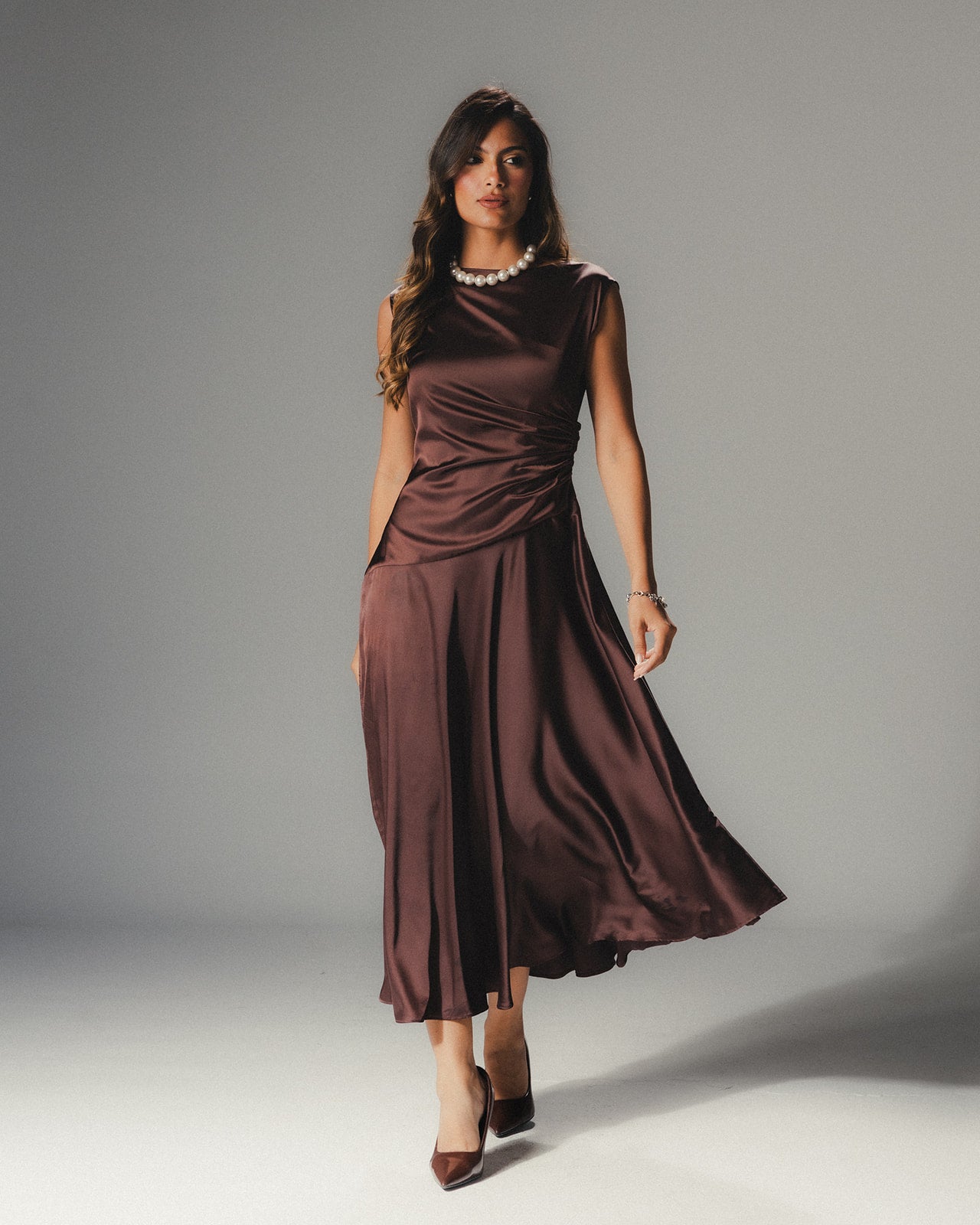 Model wearing the MYSHA Espresso brown Satin Armani midi dress featuring a high-neck and architectural drape.