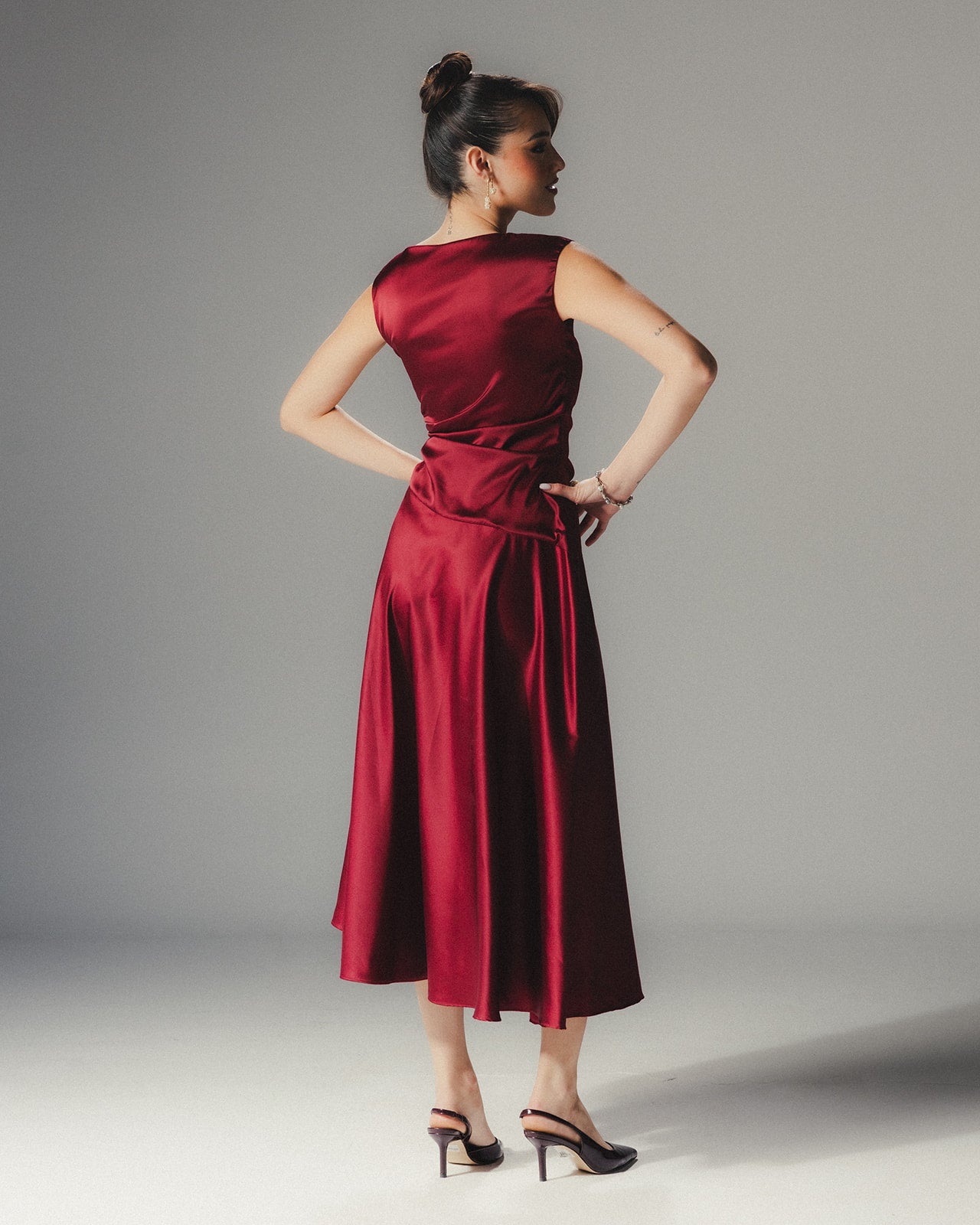 Model in the MYSHA ruby red Satin Armani midi dress demonstrating the fluid movement of the asymmetrical hem