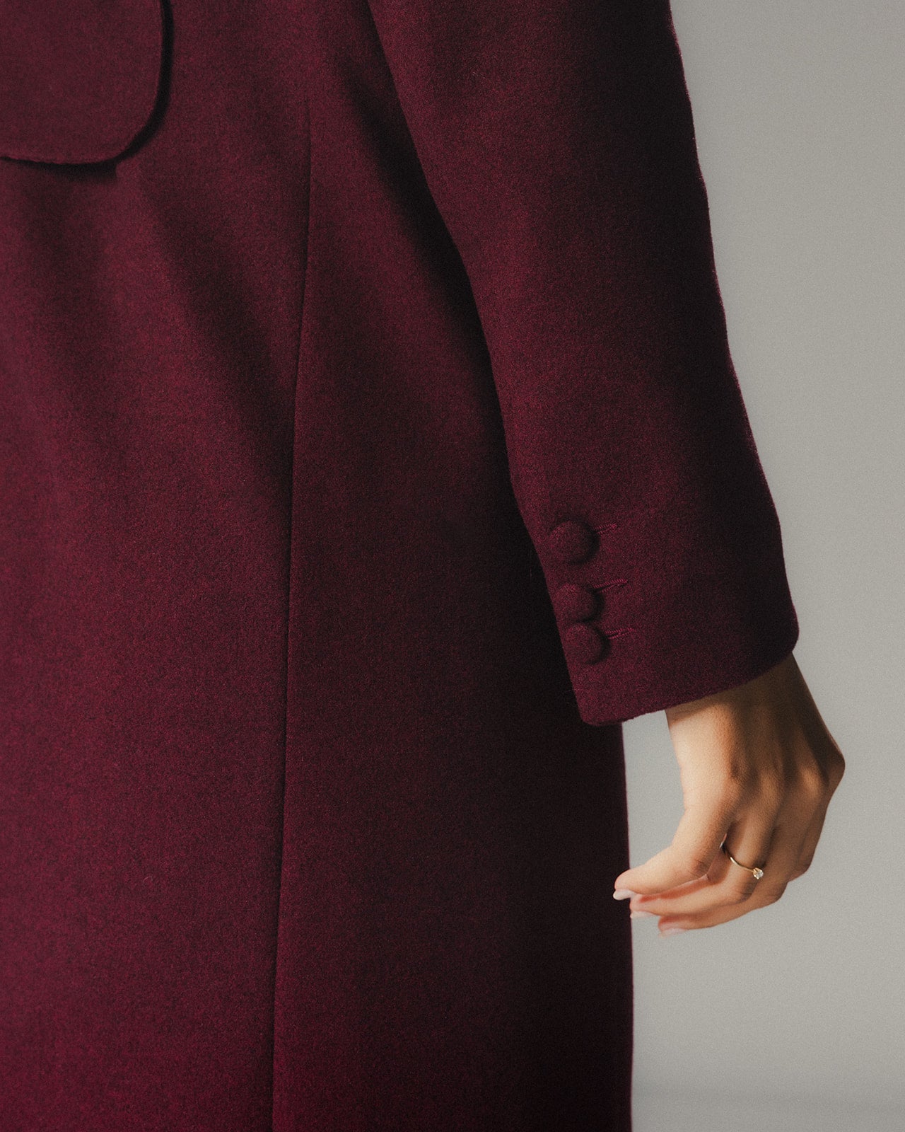 Close-up of a burgundy coat with buttons on a neutral background