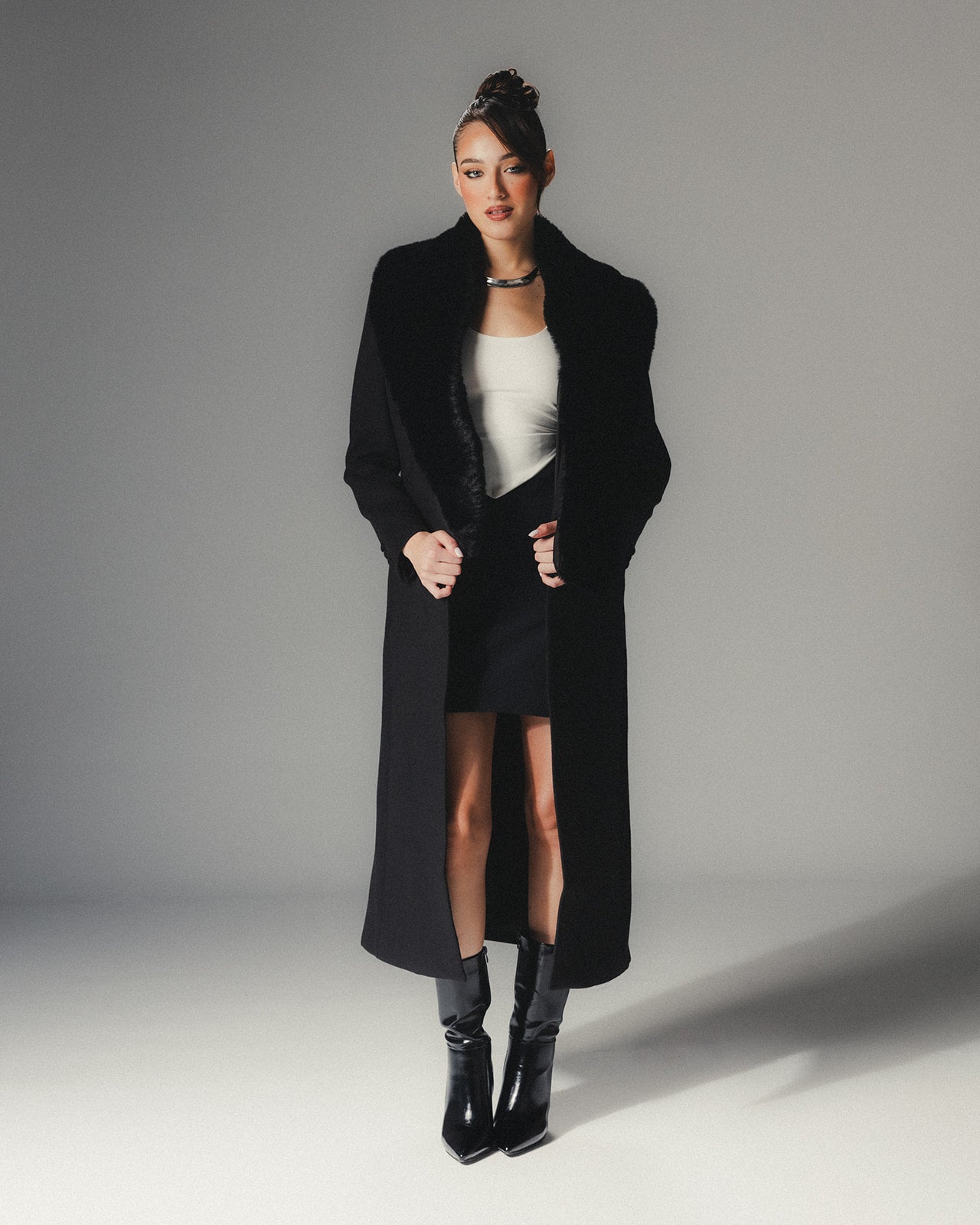 Front view of MYSHA Obsidian black premier wool coat with plush detachable fur collar on a high-fashion model.