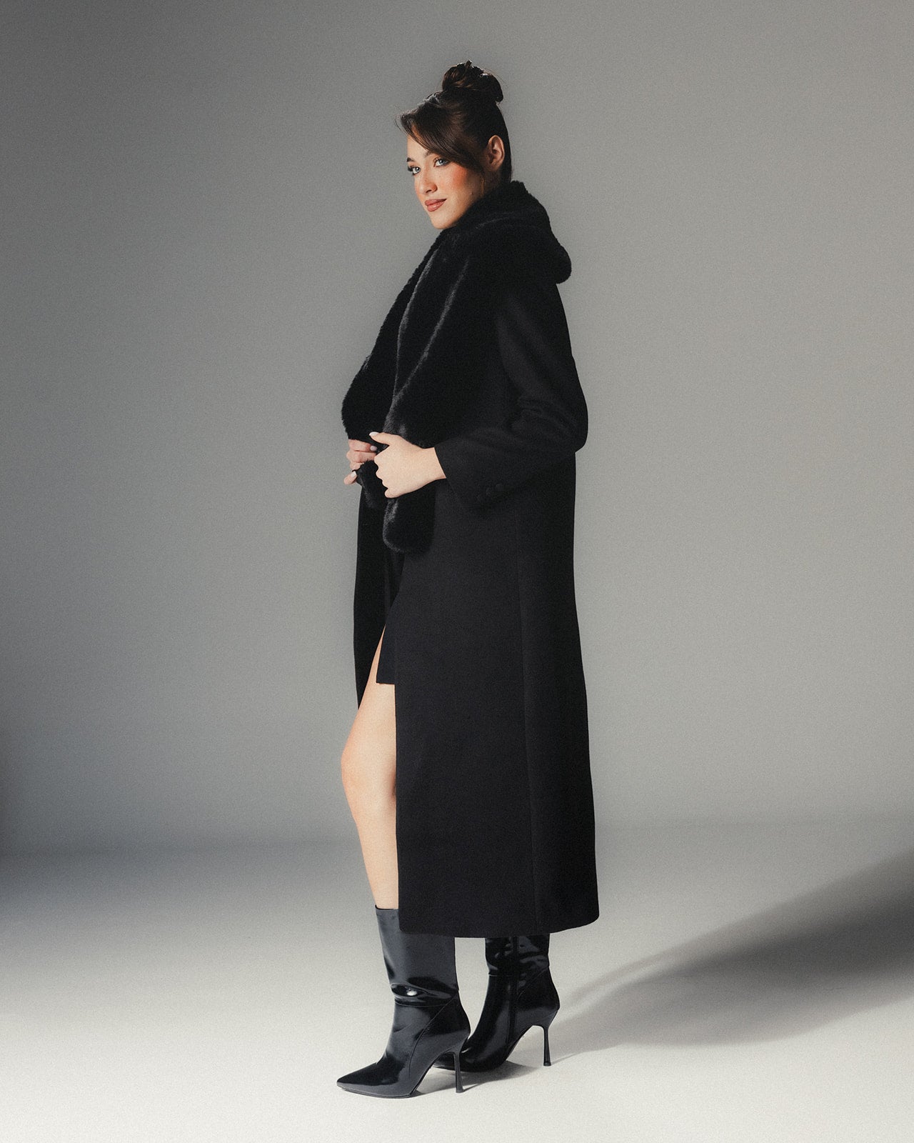 Side view of MYSHA Obsidian black premier wool coat with plush detachable fur collar on a high-fashion model.