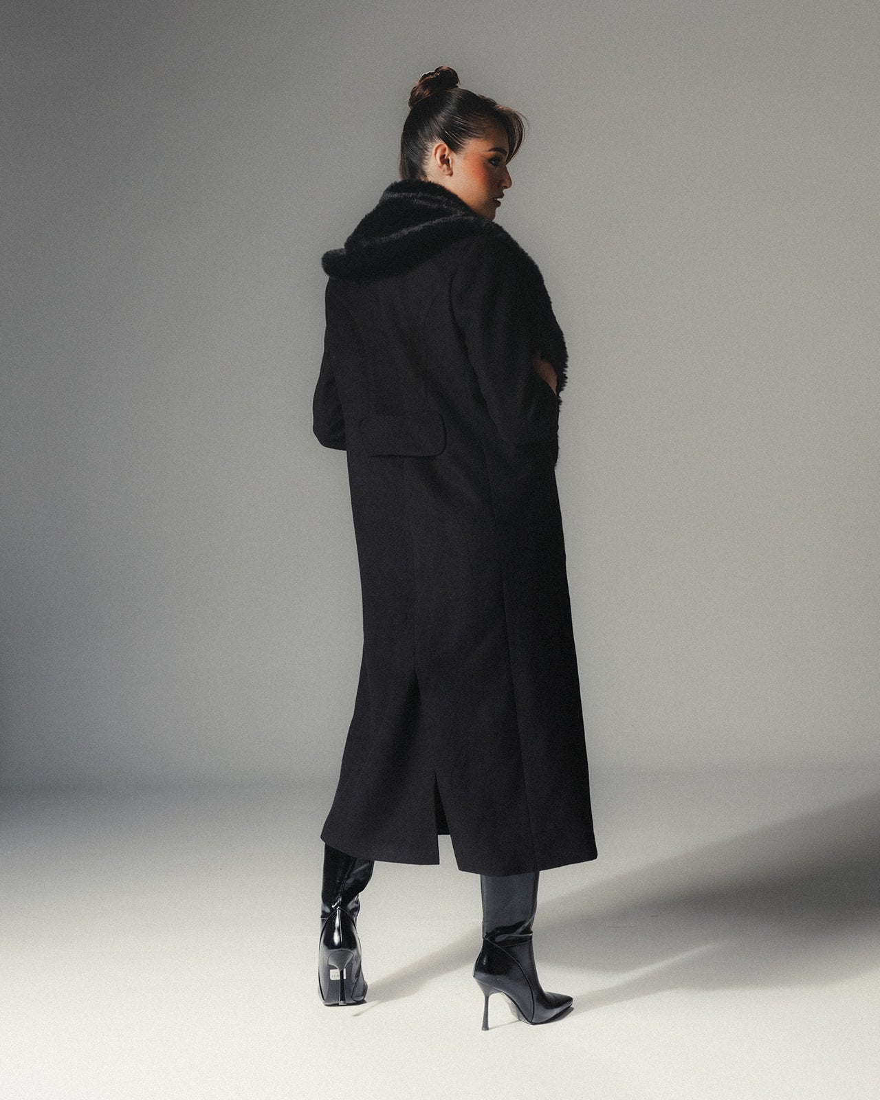 Back view of MYSHA Obsidian black premier wool coat with plush detachable fur collar on a high-fashion model.