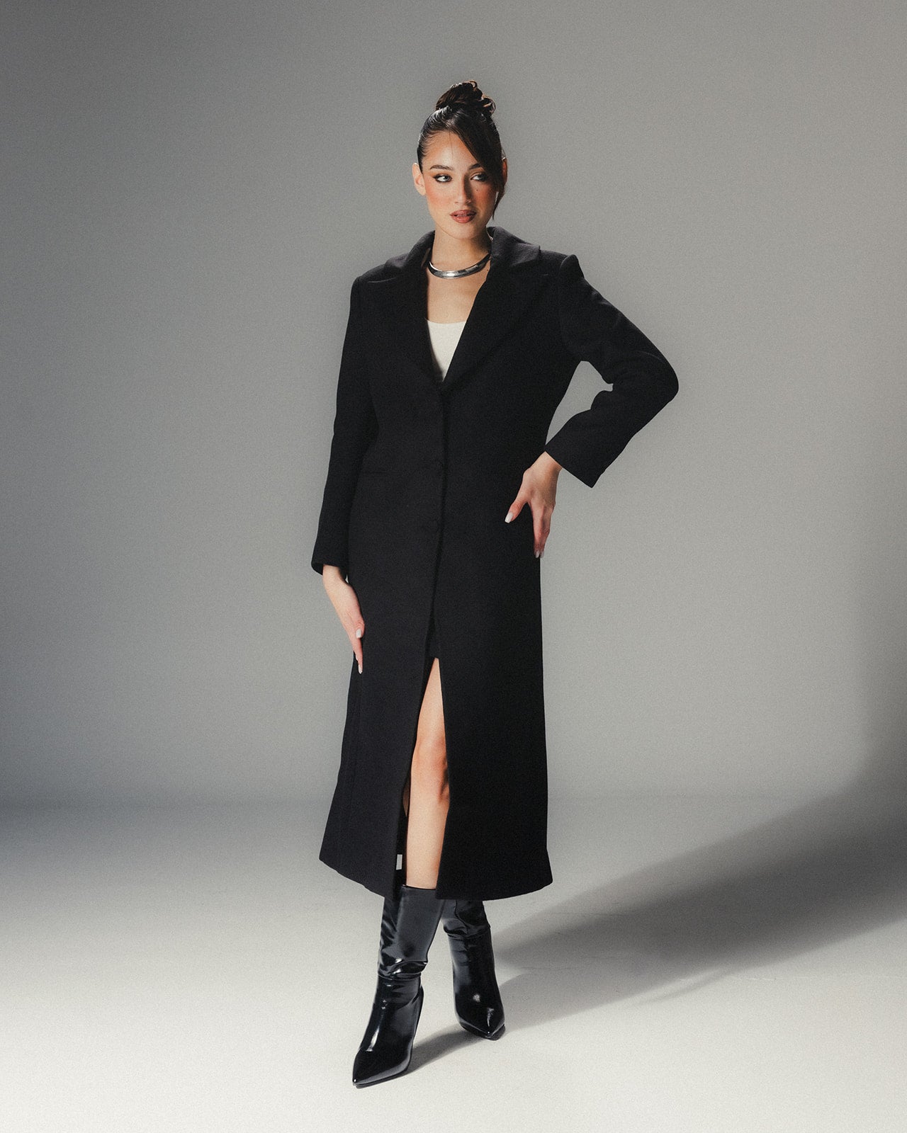 Close-up of the minimalist lapel and tailoring of a high-end black wool coat without the fur attachment