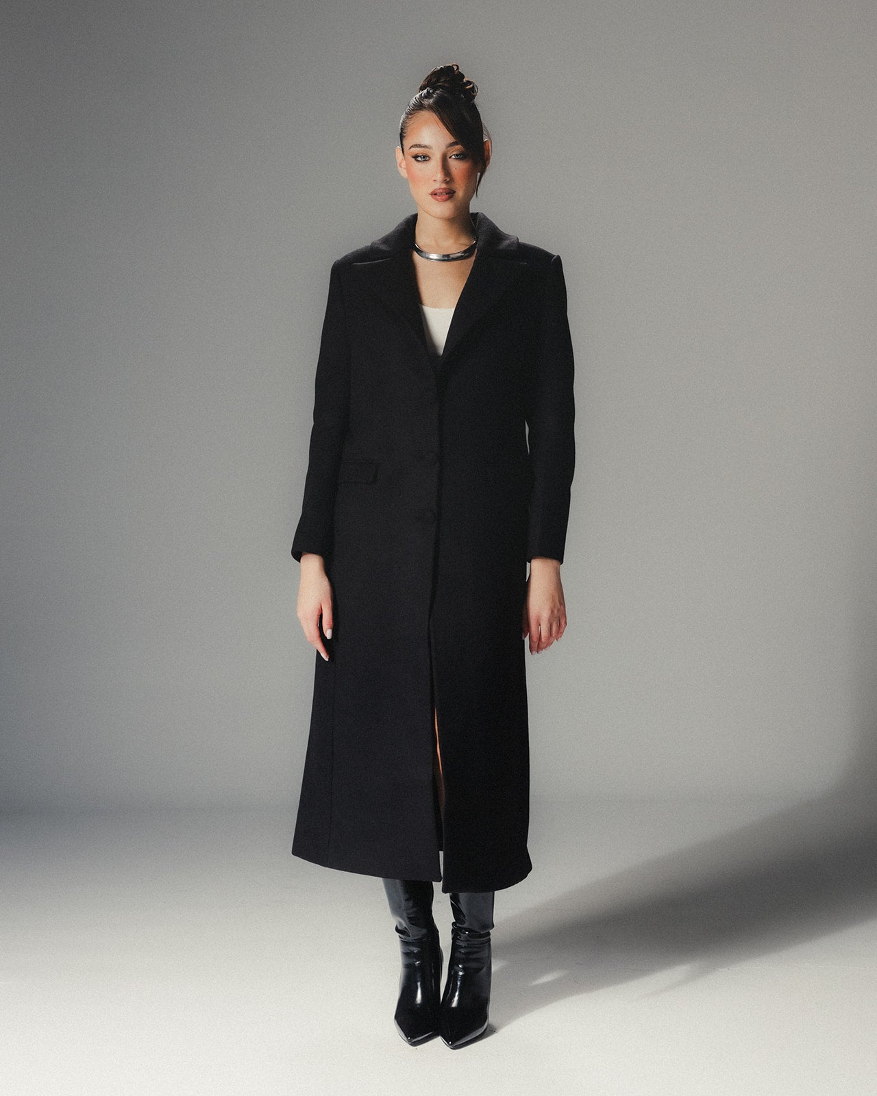 Close-up of the minimalist lapel and tailoring of a high-end black wool coat without the fur attachment