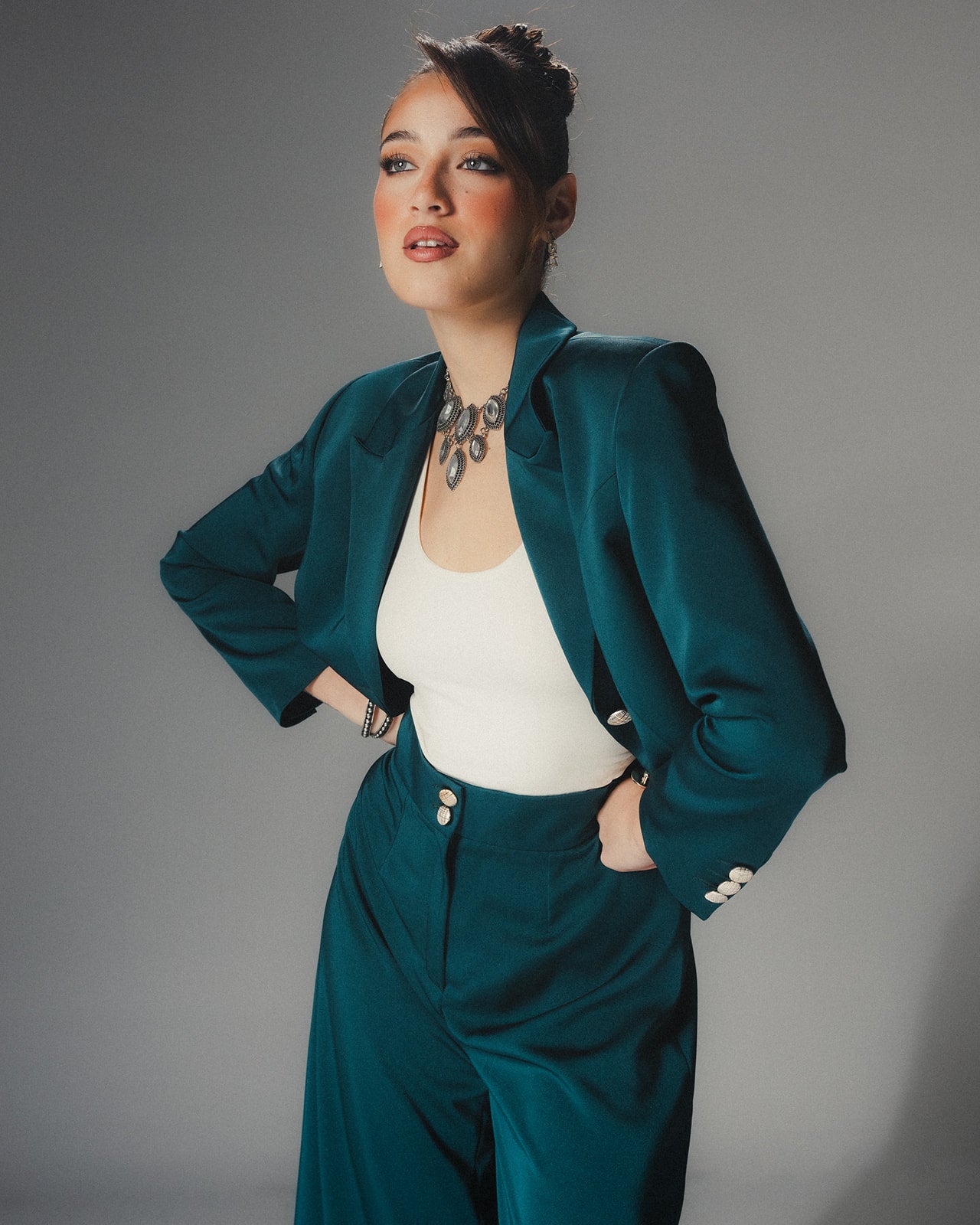 Front view of MYSHA Emerald green cropped blazer in luminous satin crepe featuring sharp lapels and silver-toned statement buttons.