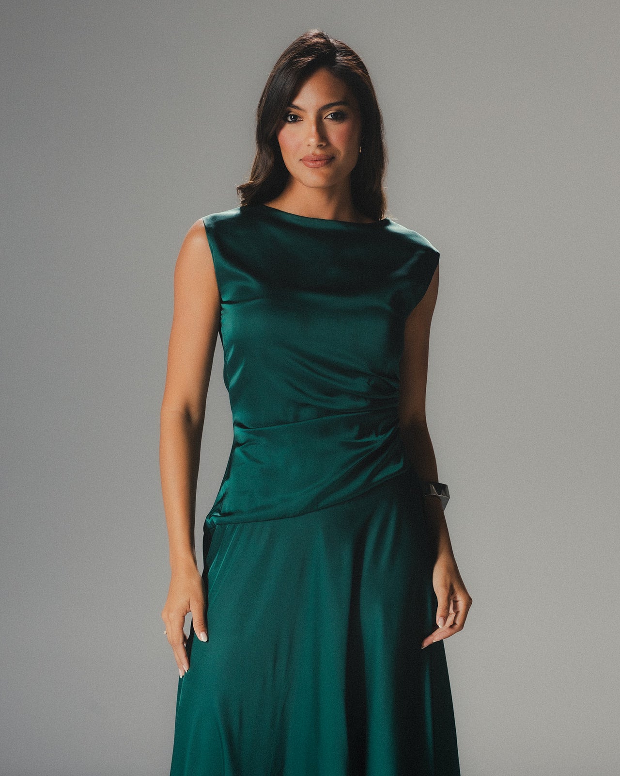 Close-up of the high-neckline and sleeveless detail of the MYSHA emerald green satin dress.