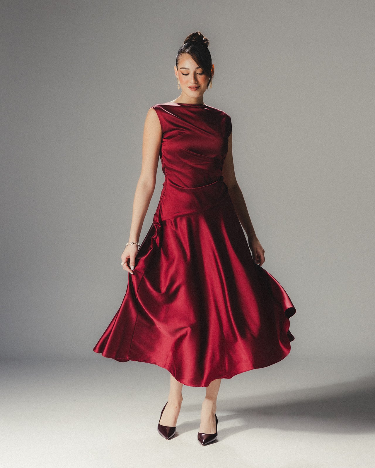 Model in the MYSHA ruby red Satin Armani midi dress demonstrating the fluid movement of the asymmetrical hem