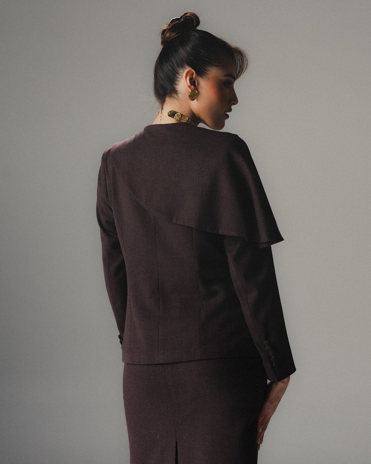 Back view of model wearing the MYSHA Espresso brown blazer and matching tailored skirt